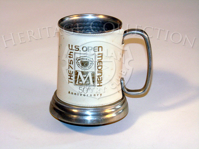 A metal drinking mug with glass bottom and leather sleeve from the 75th U.S. Open.