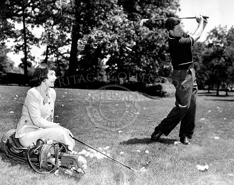 Original Associated Press Photo caption read: NUMBER ONE FAN WATCHES HARBERT--Melvin (Chick) Harbert (right), Northville, Mich., brushes up on his iron shots at Medinah Country Club near Chicago, June 7, as his wife, Jeanne, beams approval. Harbert will compete in the National Open tournament which begins June 9 at the Medinah course.