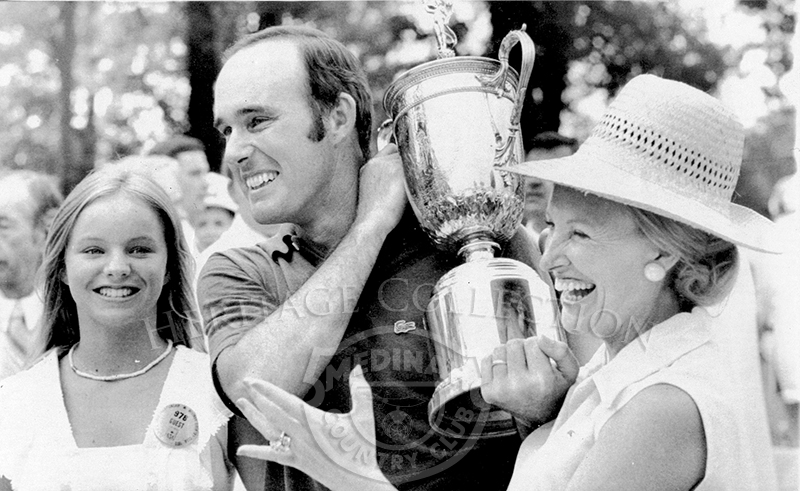 Lou Graham is flanked by his daughter, Louanne, left, and his wife, Patsy, as he carries the U.S. Open trophy after winning the playoff at Medinah Monday.