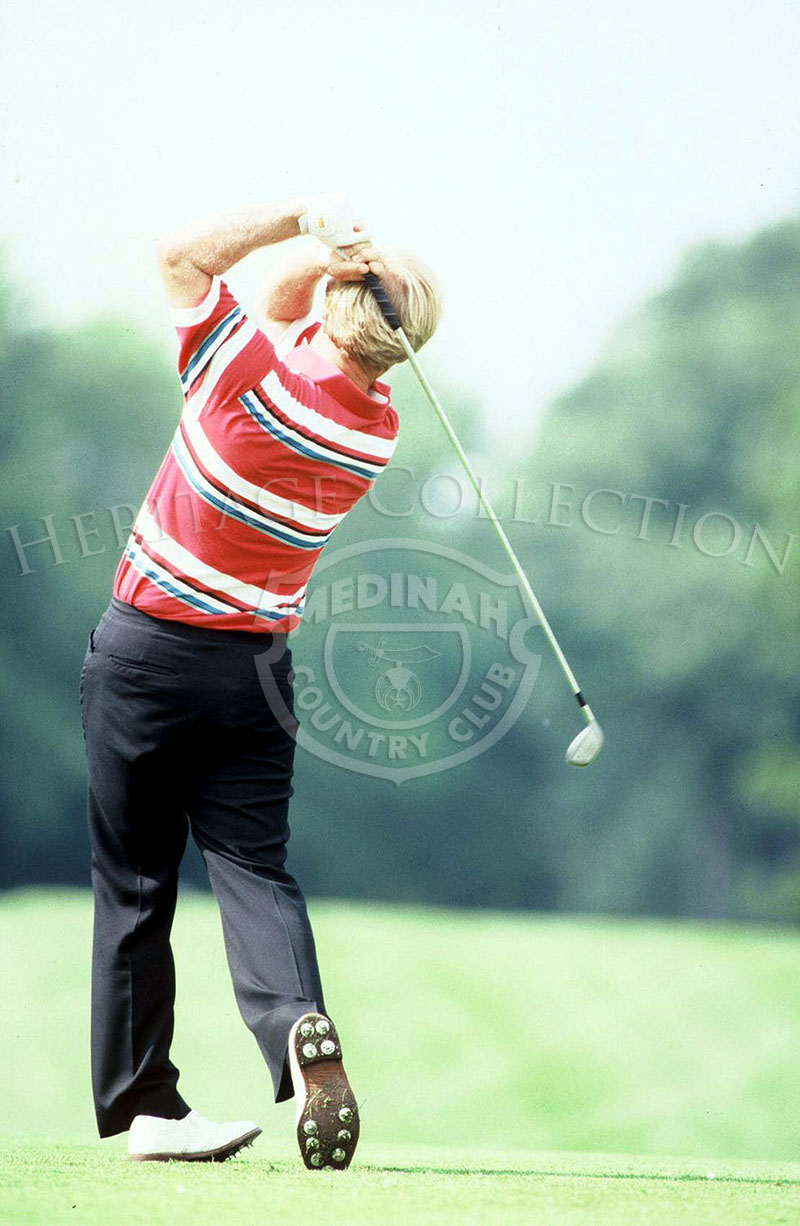 A rare view from behind Jack Nicklaus, shows his golf swing while using an iron, as he blasts a ball down one of the fairways during play at the 90th U.S. Open Championship.