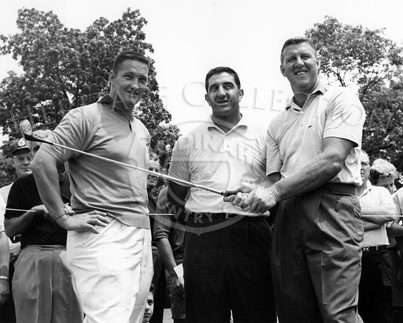 With club in hands, George Bayer, the six foot, five inch professional golfer, posed with two unidentified men during the 59th Western Open in 1962.
